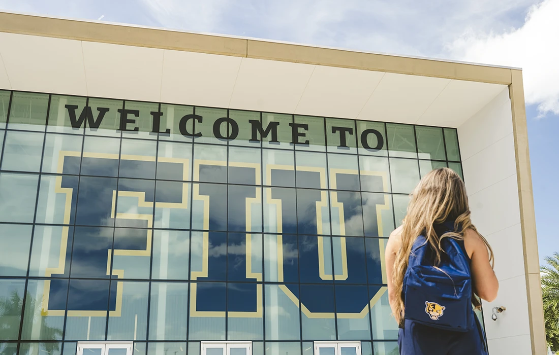 FIU student looks up at the Welcome to FIU sign at at the Student Academic Success Center